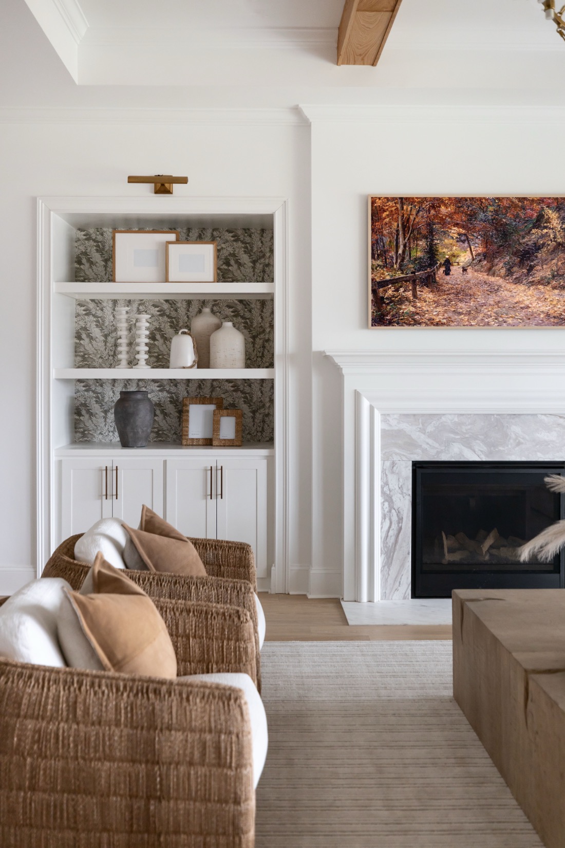 Living room with styled built-ins, a marble fireplace and woven lounge chairs, fully furnished by Kimberley Kay Interiors