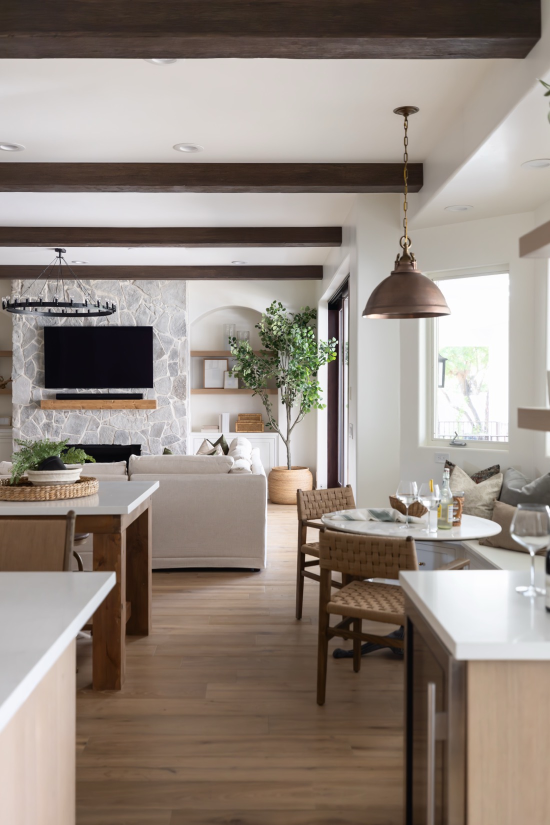 Open-plan great room with wood-beamed ceiling, stone fireplace and custom millwork, renovation and furnishings together